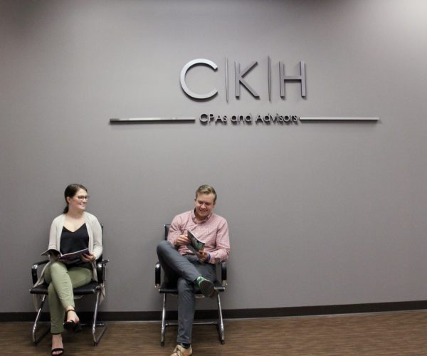 2 CKH Group employees sitting in a chair at the office at the reception area reading magazine