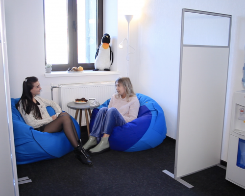 Two CKH Spain employees sitting on bean bags in the office hall and chatting